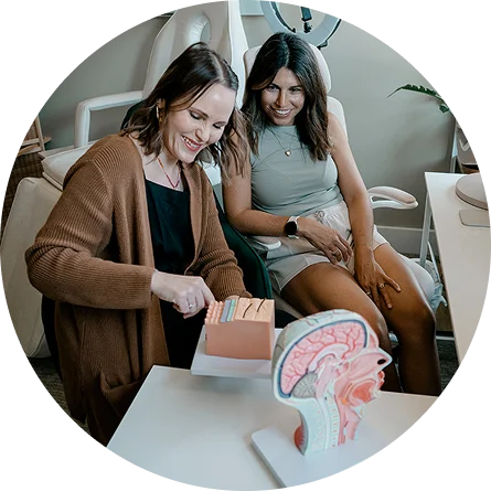 a group of women sitting at a table looking at a model of a human brain