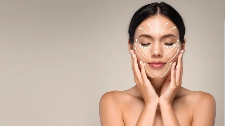 Young woman with closed eyes and skincare massage lines drawn on face, neutral background.