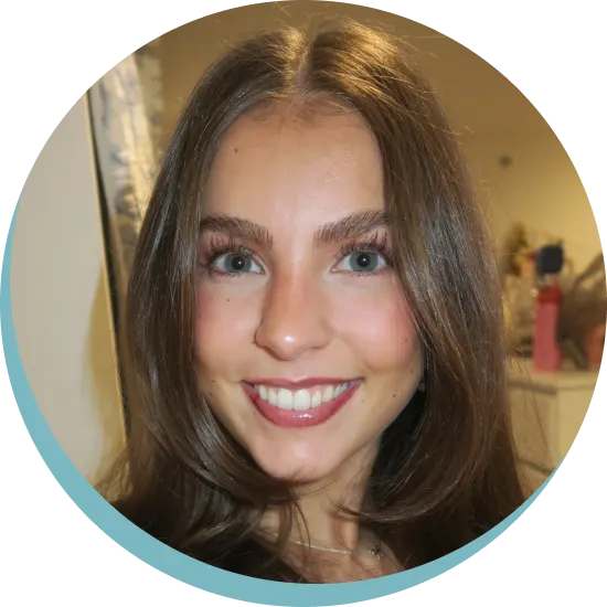 Close-up portrait of a young woman with long brown hair, blue eyes, and a bright smile.